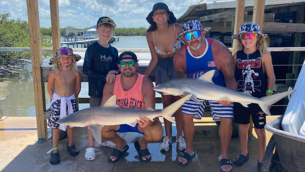 family holding two Blacknose Sharks